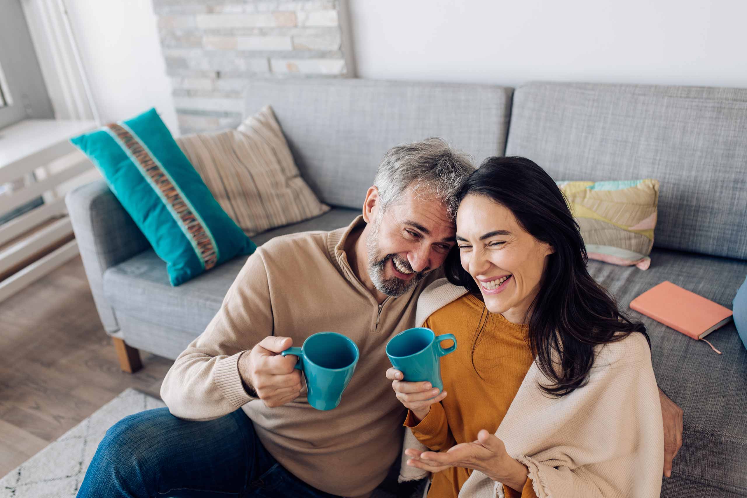 Pre-retiree couple having coffee and laughing in their home